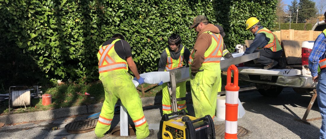 Crew putting pipe in manhole