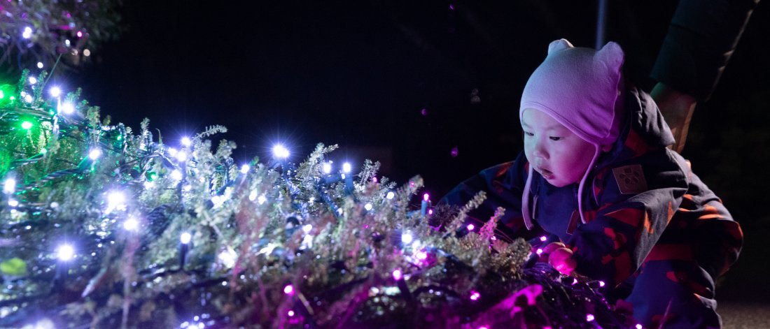 a young child crouched down admiring a light display