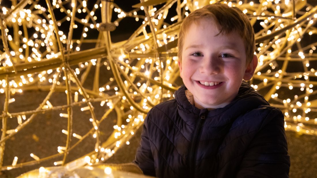boy smiles next to white lights