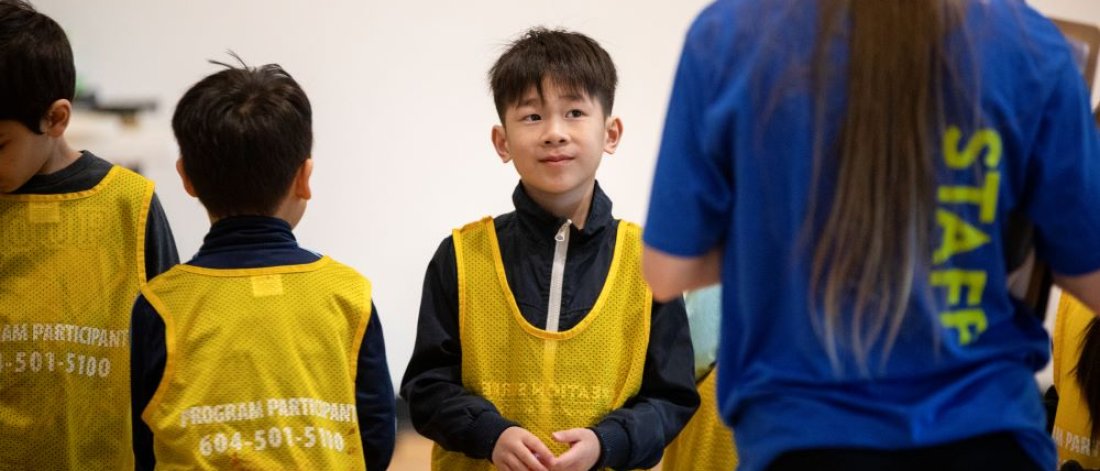 A boy listening to the leader of a children's program.