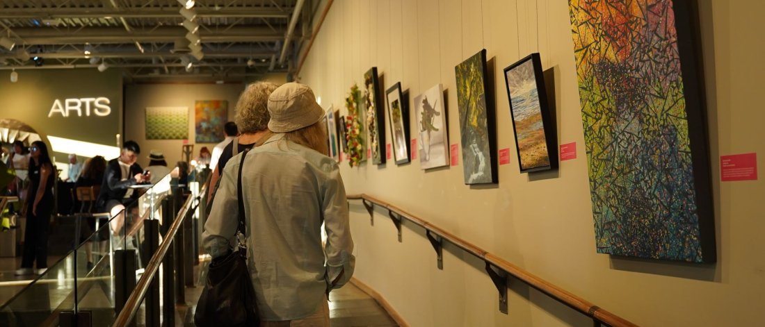 Visitors to Surrey Arts Centre line the lobby space, looking at artworks on the walls.