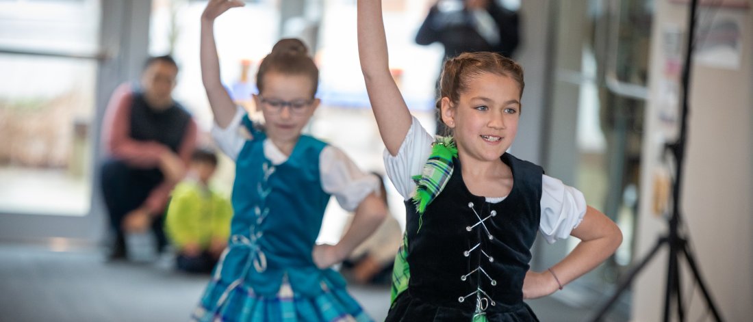 Two young girls in traditional Celtic dance attire perform.