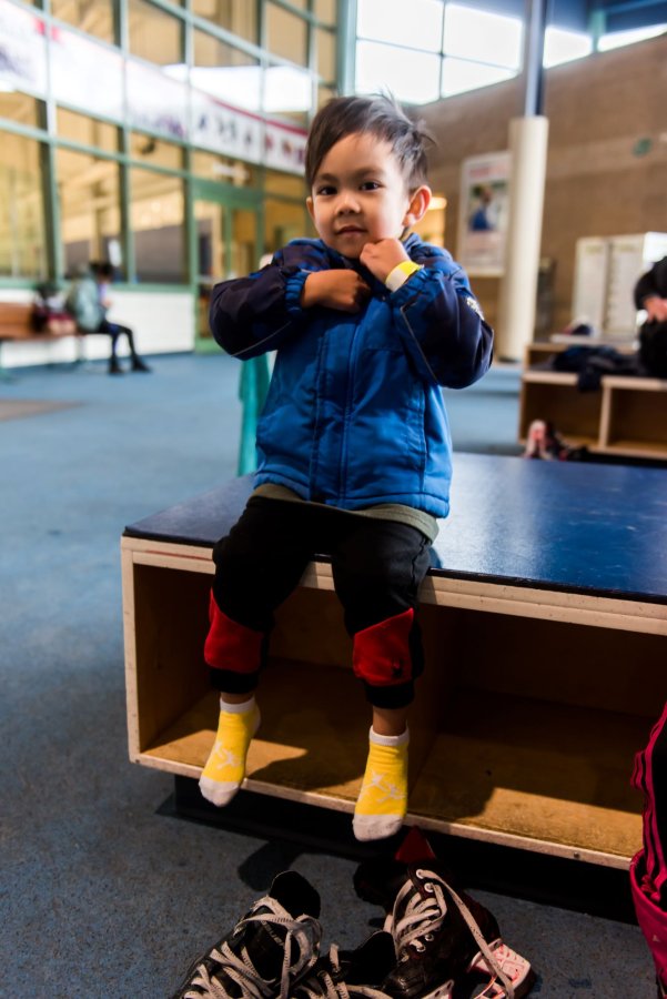 A child unzipping their jacket after skating at the ice rink.