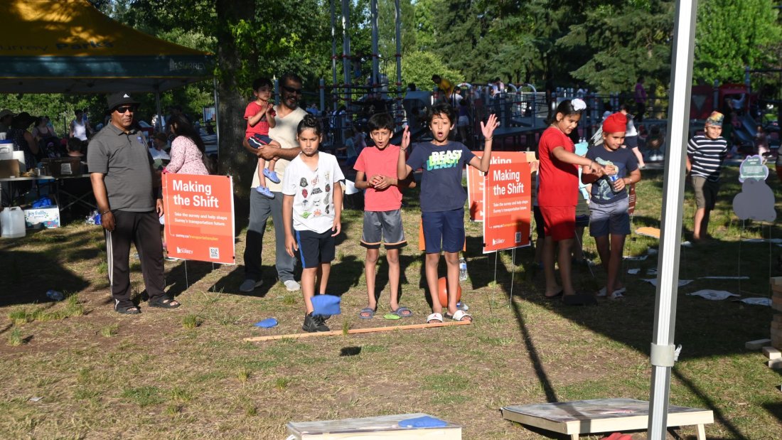 three children play corn hole. one has a surprised look on his face