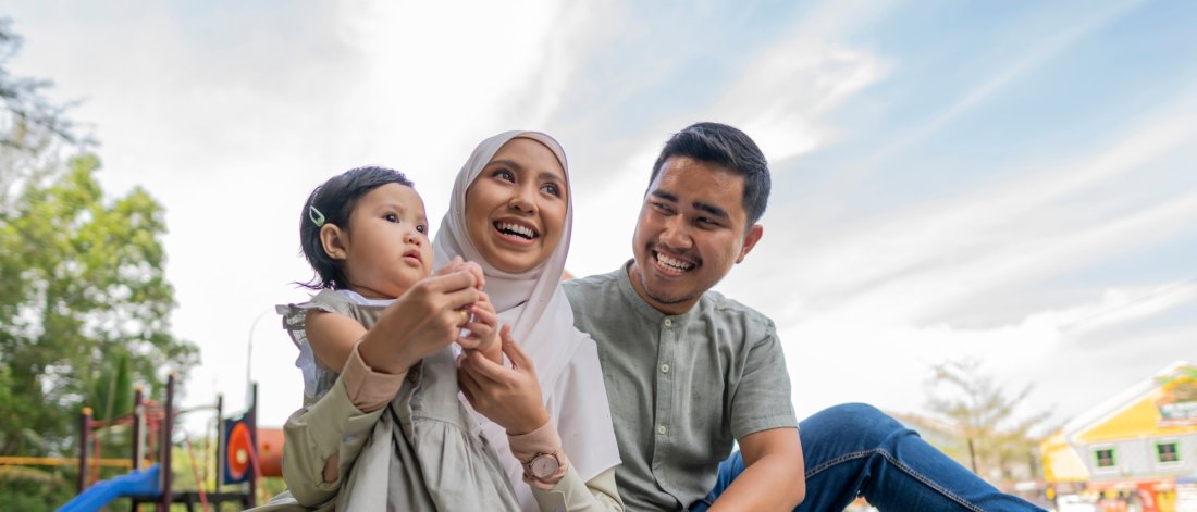 family smiling while sitting on a picnic blanket