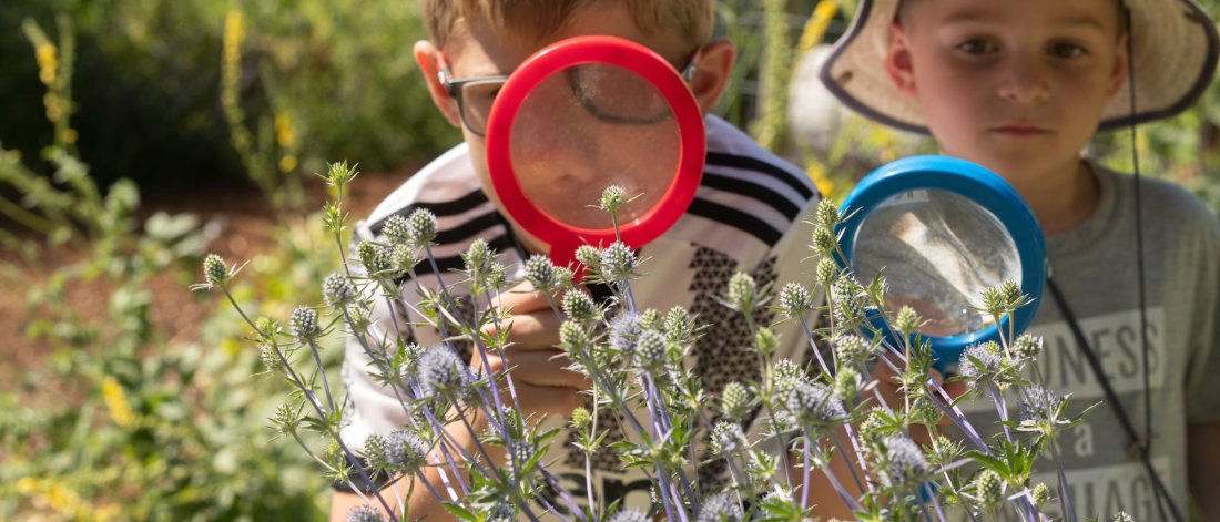 two children look at plans with magnifying glasses