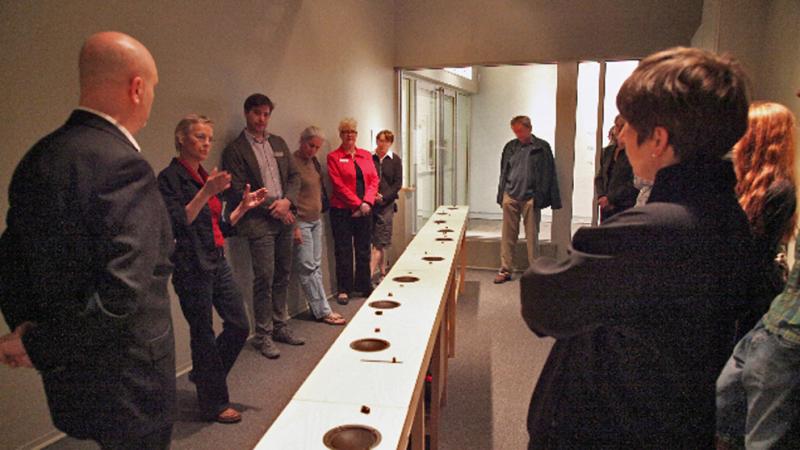 A row of people looking at a long white box