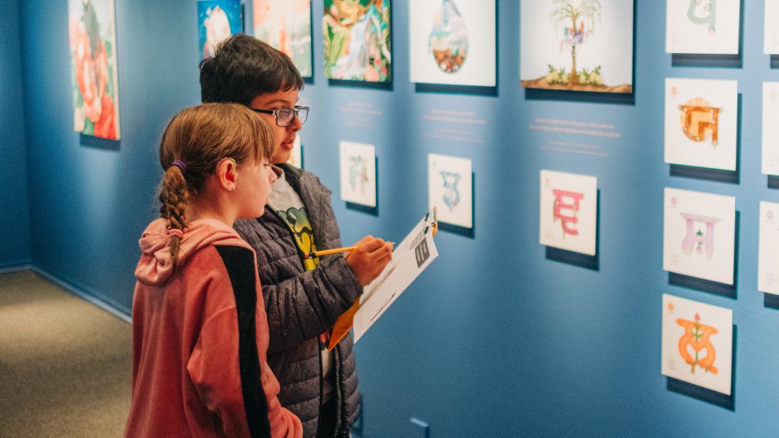 Two children are engaging in the Art Explorer Guide for Keerat Kaur: Panjabi Garden exhibit.