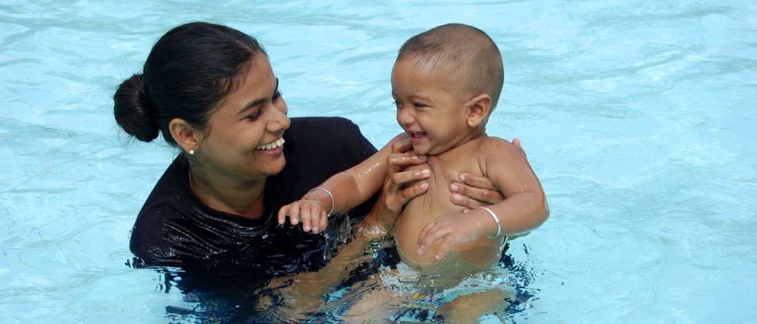 A mother swimming with their child.