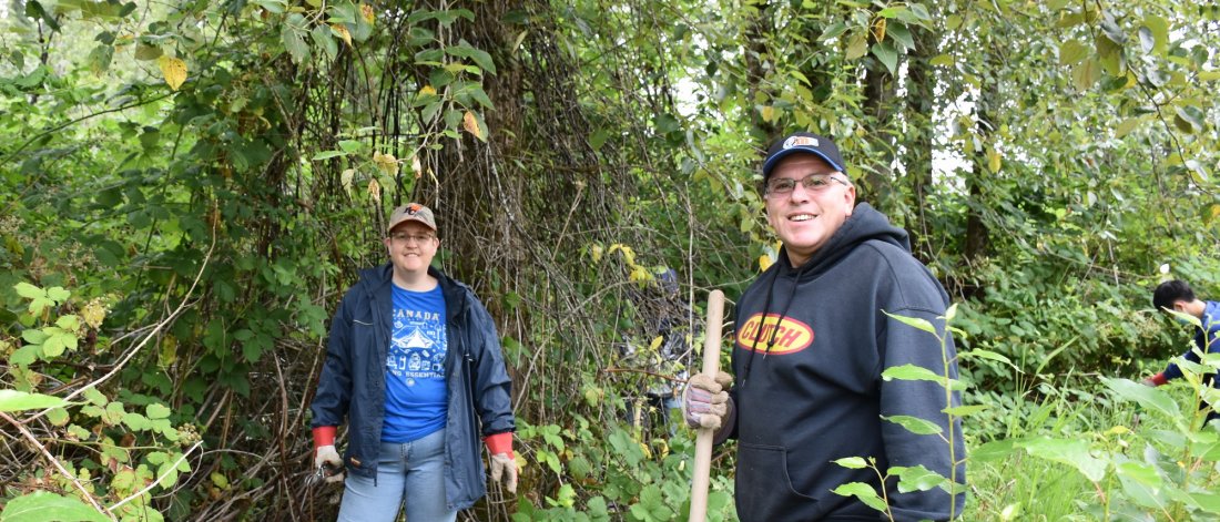 two people holding tools standing in a forest