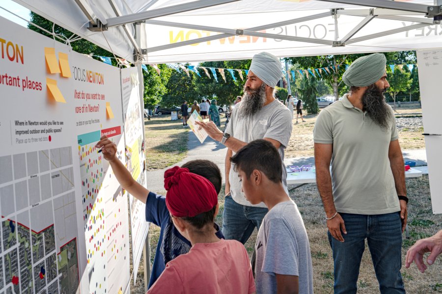 two men and a group of children look at some informational boards