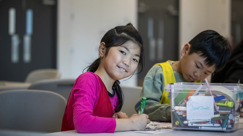 A girl smiling while making crafts.