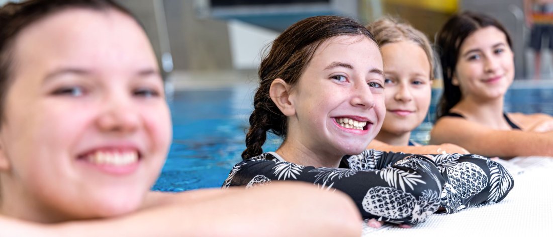Girls in the pool smiling.