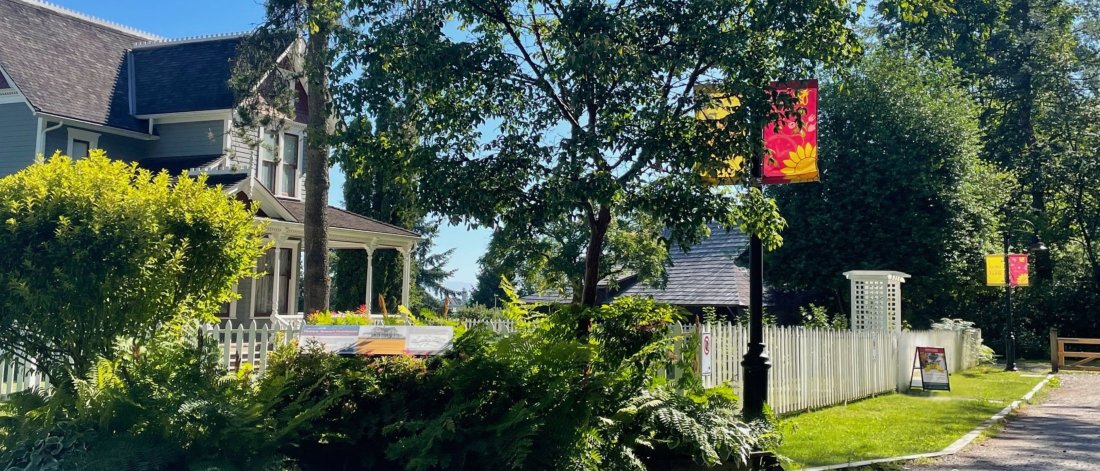 A house and a lightpost stand with greenery