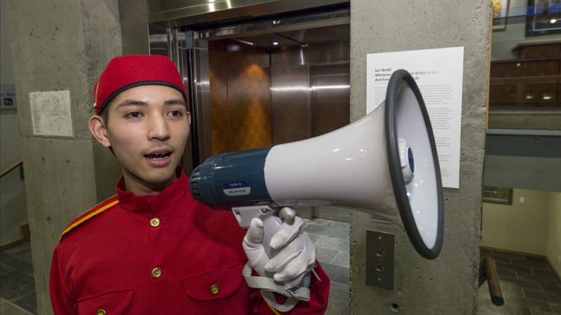 A man in a red bell boy costume with a white megaphone