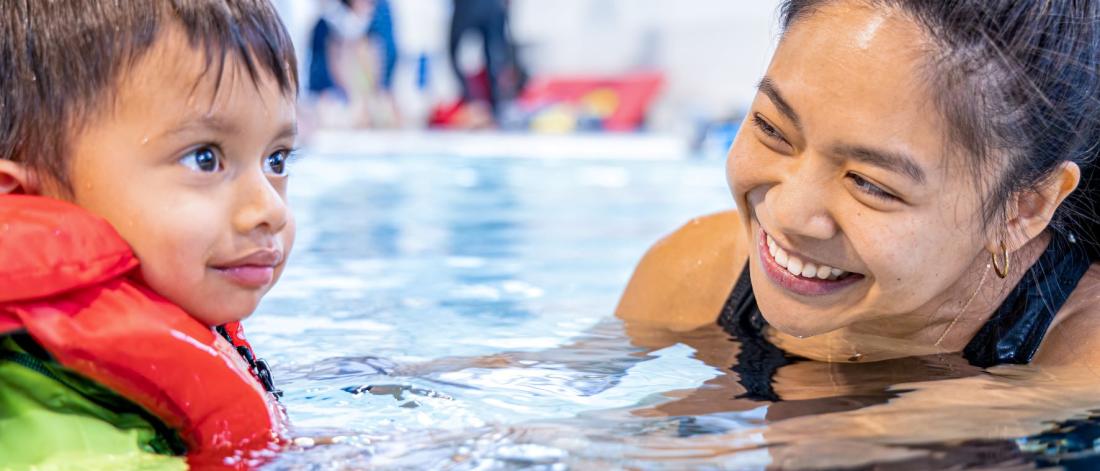 A little boy and swim instructor in a swimming lesson.