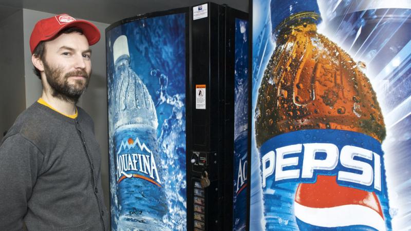 A man in a ball cap stands next to vending machines