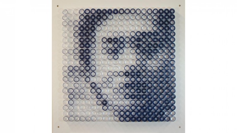A bird’s eye view of circular vinyls that form a navy and white image that is suggestive of a face with short hair. 