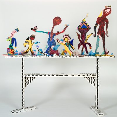 Six abstract sculptures of people stand on a table.