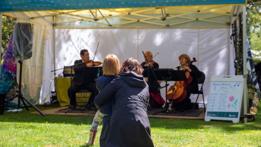 child and adult watching the musicians perform at The Glades