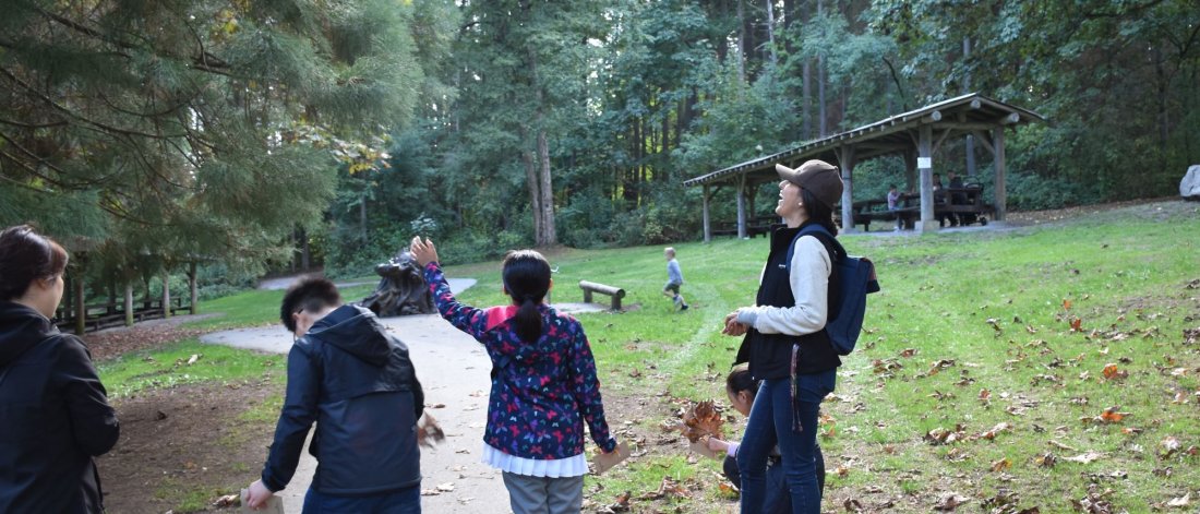 laughing teacher leads a group on a walk in a park