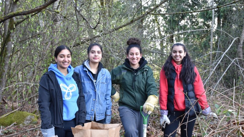Four volunteers smiling in a park.
