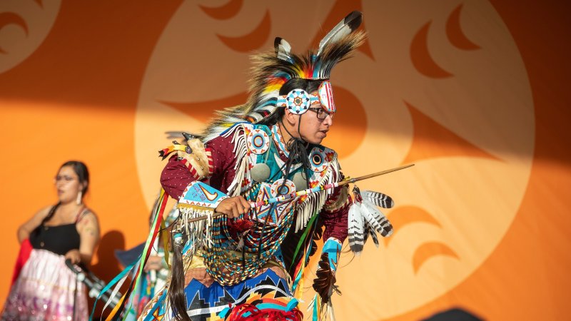 a man in a traditional indigenous outfit performing at NIPD