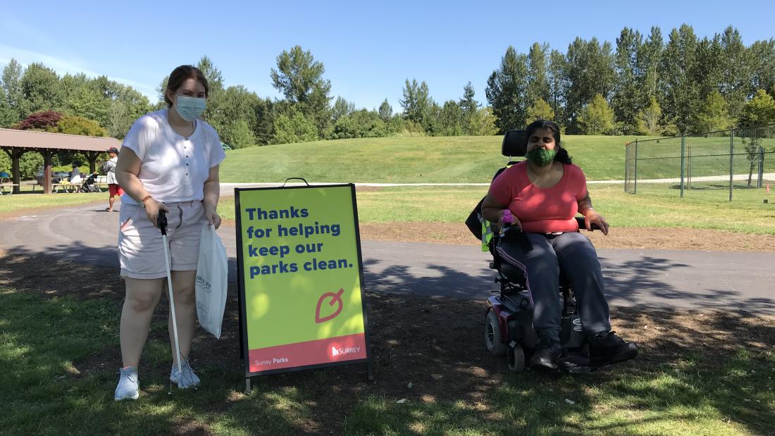Two volunteers next to a sign. 