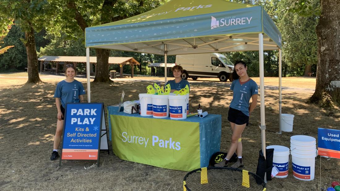 Three volunteers at a booth with a tent.