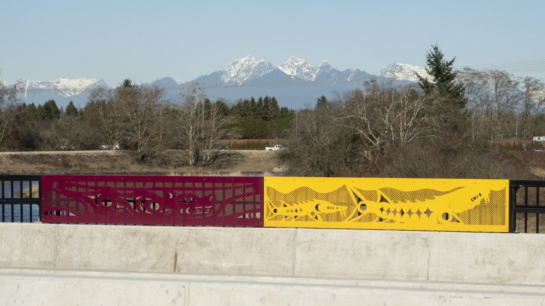 A side path with colorful barrier panels under a blue sky.