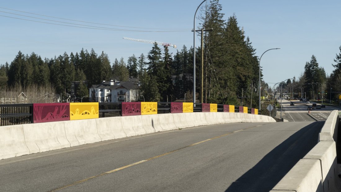 A side path with colorful barrier panels under a blue sky.
