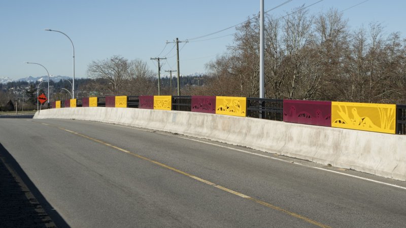 A side path with colorful barrier panels under a blue sky.