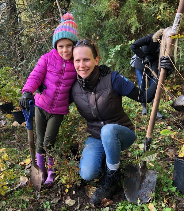 Mother and daughter plant trees in a park