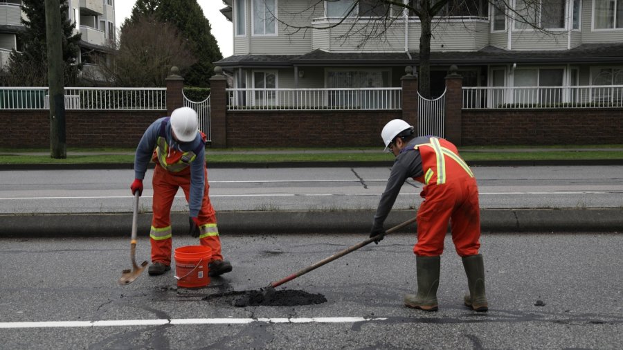 workers fill a pothole