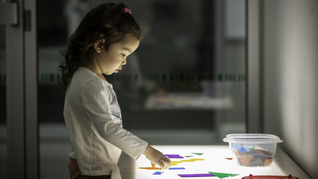 A little girl using blocks at a table.