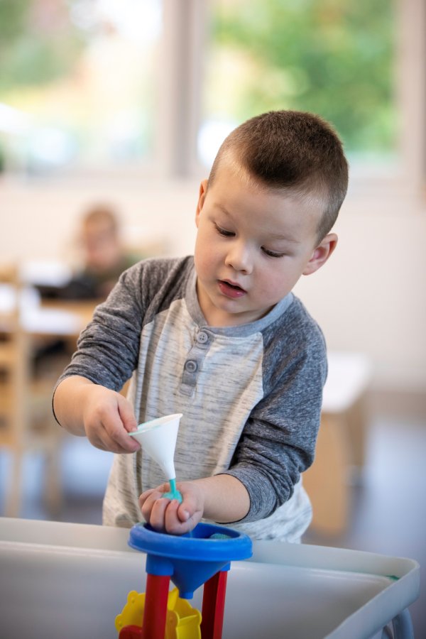 A child playing in the sand at preschool.