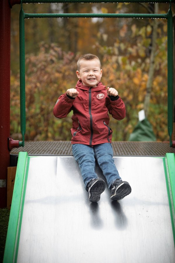A child playing outdoors, going down the slide. 