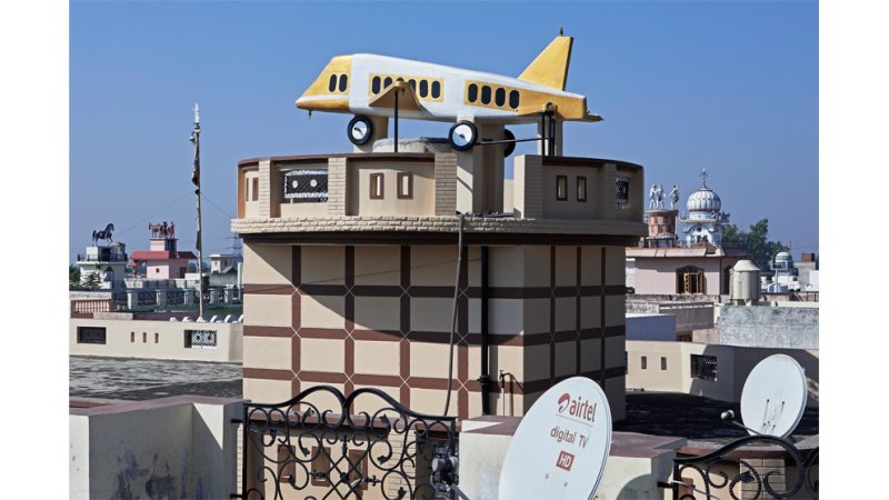 A home with an airplane fixed on top of the roof. 