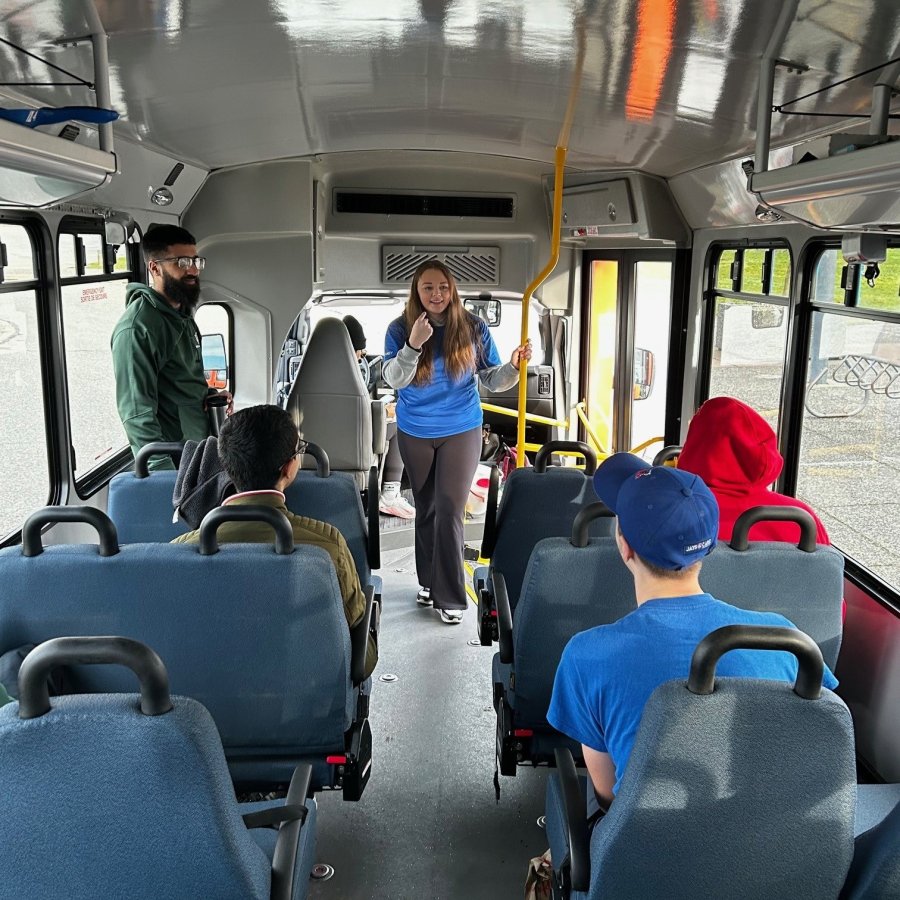 A leader at the front of the bus with four people sitting and facing them.