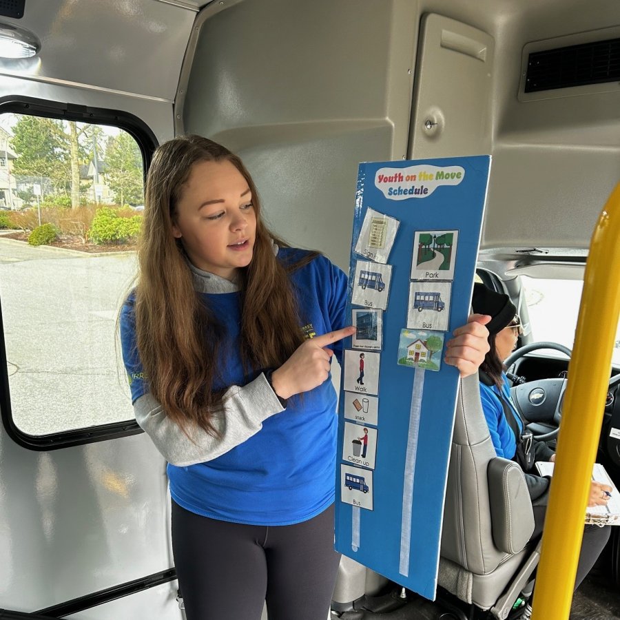A person in a blue t-shirt pointing at a poster board.