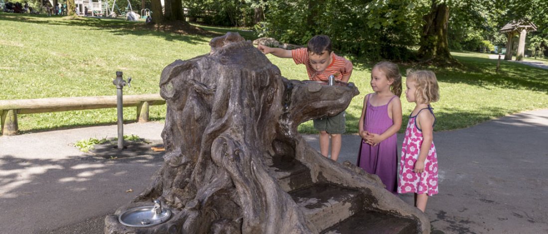 Kids drinking from a water fountain that is also a public art piece