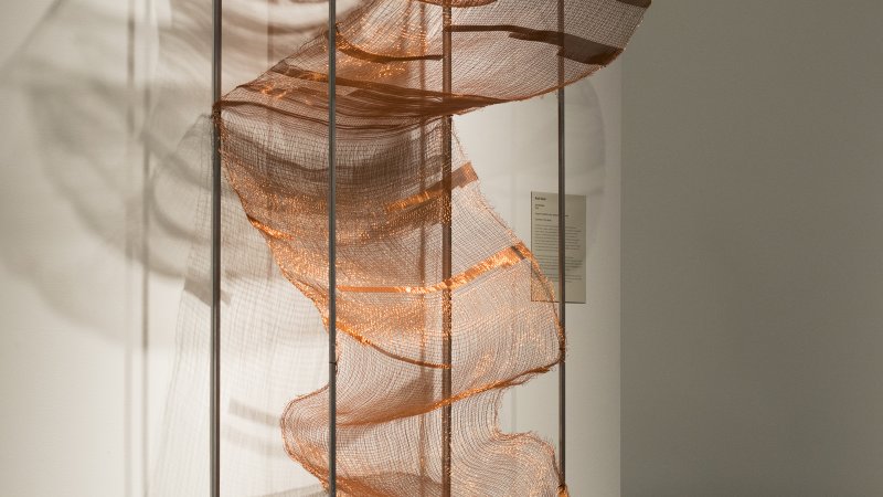 Shimmering copper coils are supported by rods.