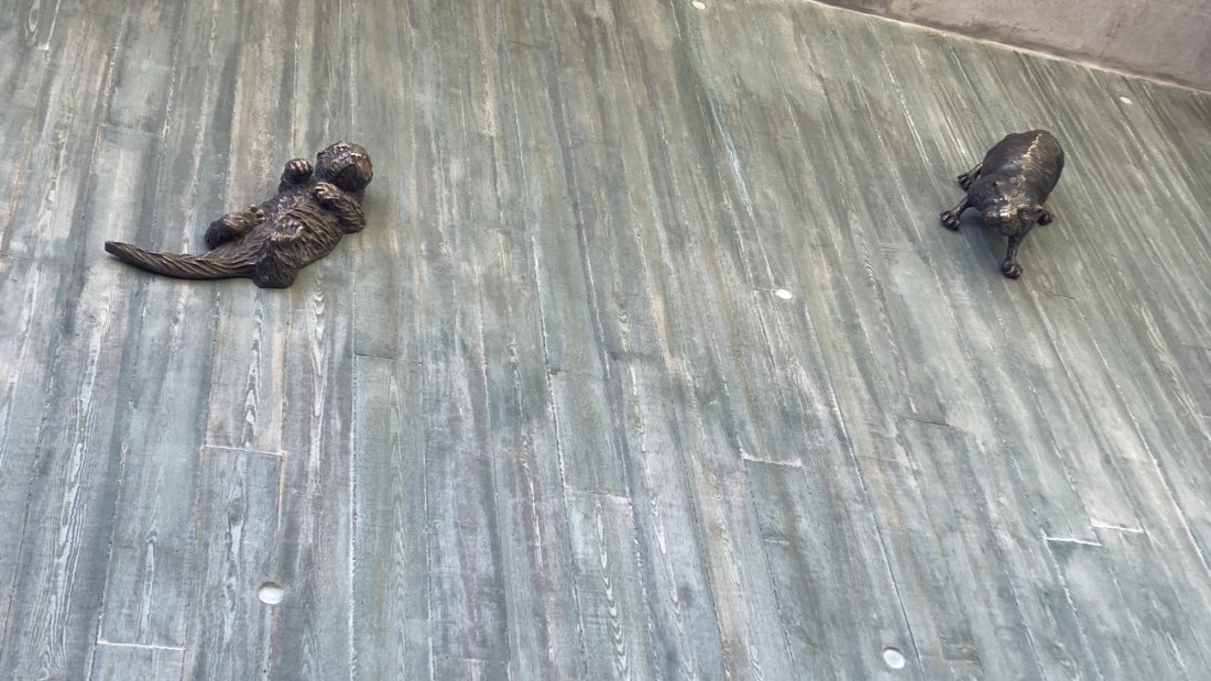 Three bronze sculptures placed on a textured concrete floor.