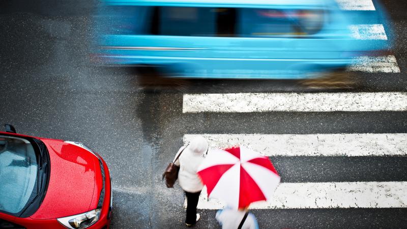 A topical view of a person in a crosswalk during rainfall