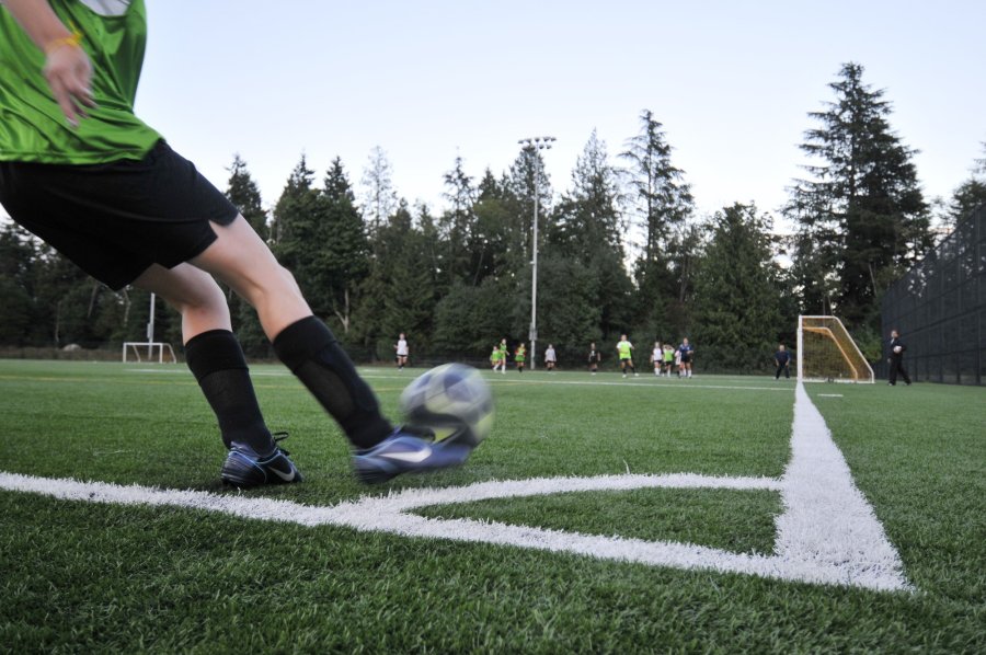 person kicking soccer ball on outdoor field