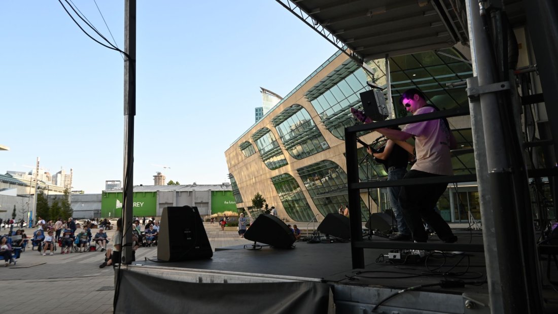 a band plays on an outdoor stage to a plaze