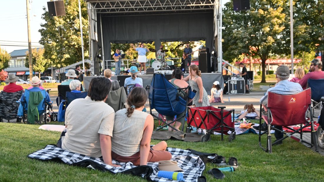a crowd watches a band on an outdoor stage