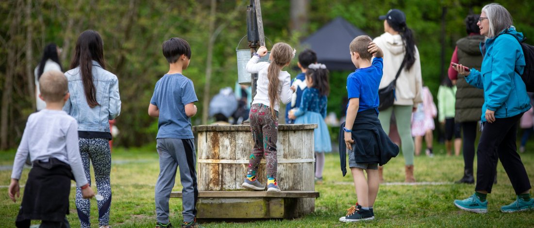 Kids gathered around the water pump at Spring Fest