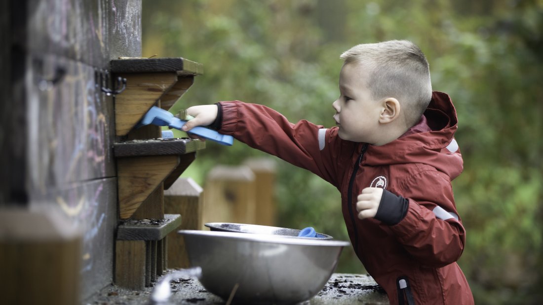 A kid playing in a pretend kitchen.