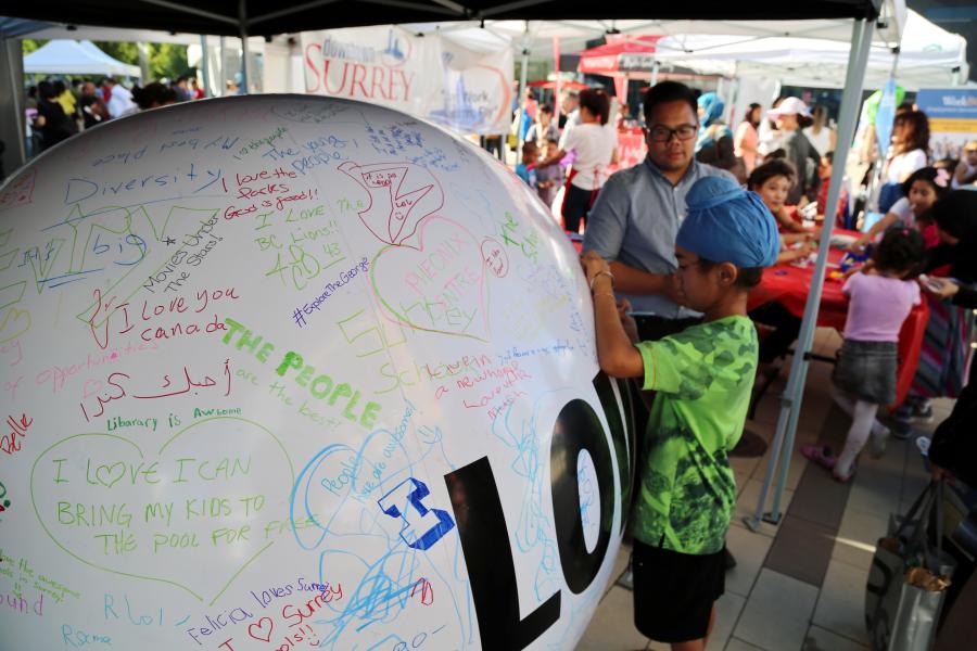 A young refugee signs a poster at a public event
